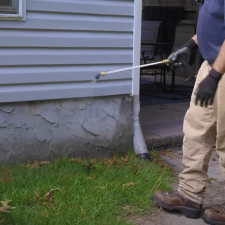 Pest control worker treating the outside foundation of a Reston-area home